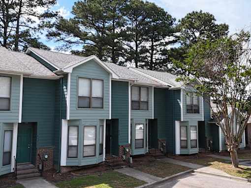 A row of houses with green siding and white trim.