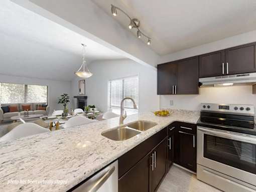 A modern kitchen with a marble countertop and stainless steel appliances.