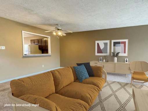 A living room with a brown couch and a ceiling fan.