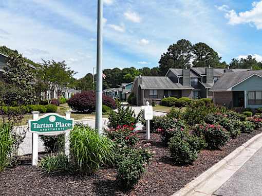 A sign for Tartan Place Apartments is in front of a well-manicured garden.