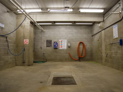 a carwash with two orange hoses and two white signs on the wall