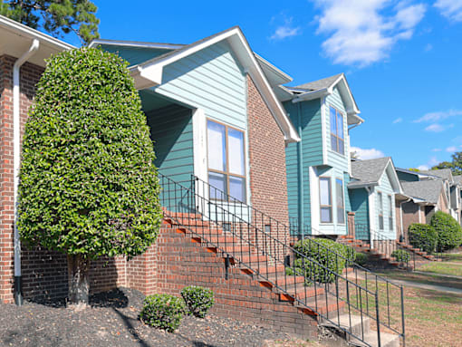 An apartment building with a blue siding  and brick details