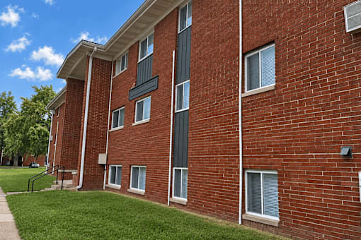 A red brick building with a green lawn in front.