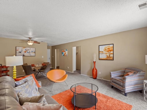 a living room with a couch and chairs and a ceiling fan