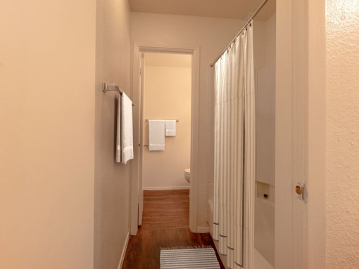 a hallway with a white shower curtain and white towels