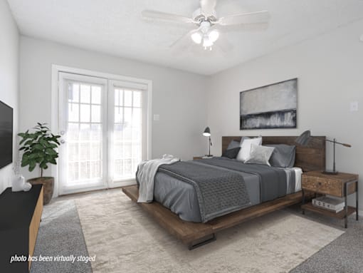 A bedroom with a bed, nightstand, and a ceiling fan.