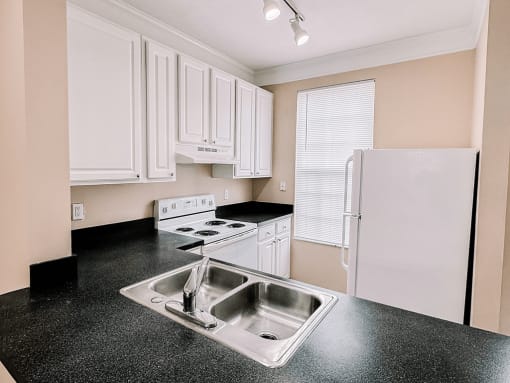 a kitchen with white cabinets and black counter tops and a sink