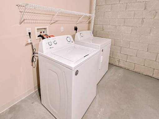 two washers and a dryer in a laundry room with a rack on top