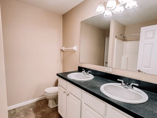 an empty bathroom with two sinks and a toilet