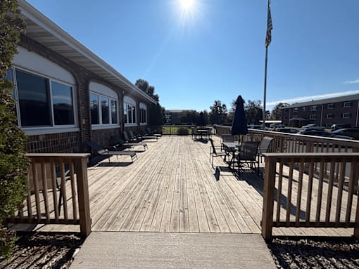 A wooden deck with chairs and a flag on a sunny day.