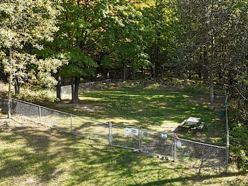 A fenced-in area with a picnic table in the middle of a grassy field.