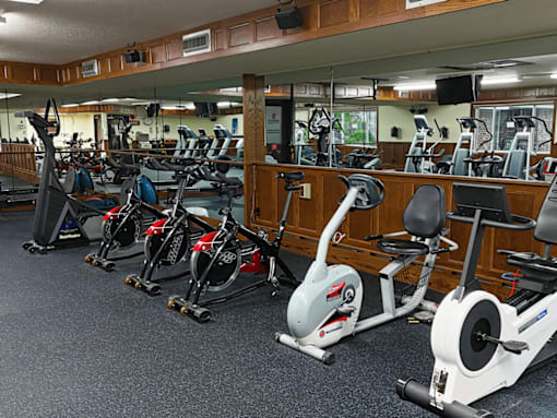 A gym with a variety of exercise equipment including treadmills, stationary bikes, and elliptical machines.