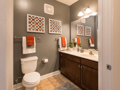 A bathroom with a toilet, sink, and towel racks.