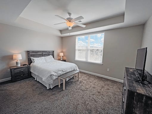 A bedroom with a bed, nightstand, and window.