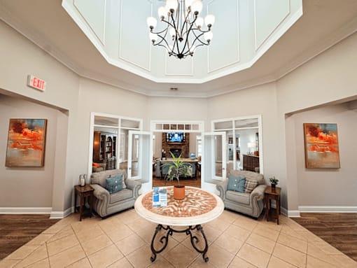 clubhouse area with a large, well-lit room with a chandelier, two couches, and a coffee table.