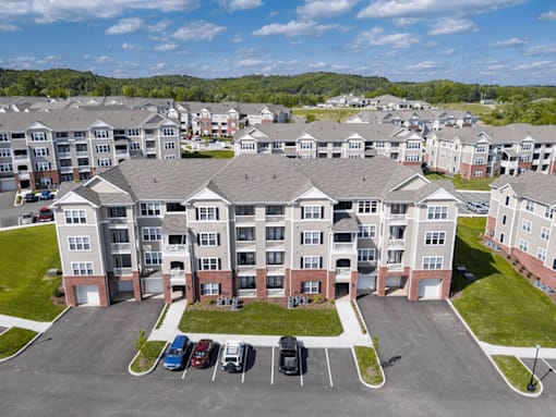 A large apartment complex with a parking lot in front.