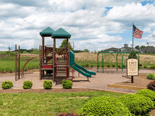 A playground with a green slide and a wooden structure with a red roof.
