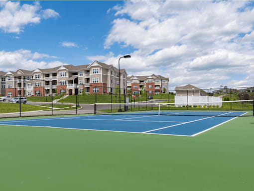 A tennis court in front of apartment buildings.