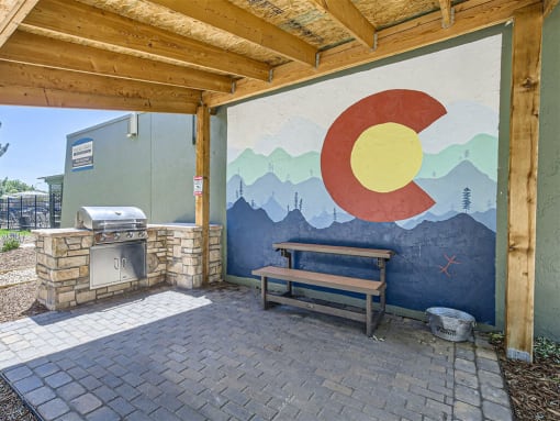 a picnic table in front of a mural on a building with a Grill