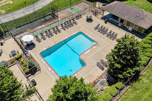 A large outdoor swimming pool surrounded by a fence and lounge chairs.