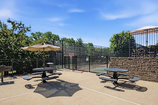A sunny day at the park with picnic tables and an umbrella.