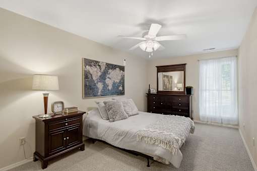 A bedroom with a bed, dresser, and ceiling fan.