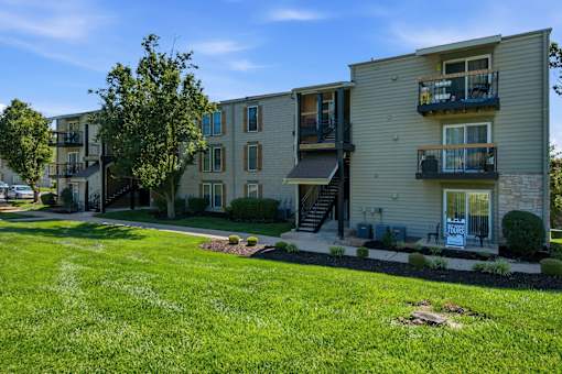 Apartment complex with a grassy front yard and a clear blue sky.