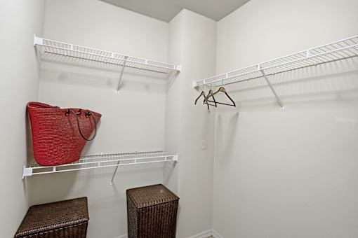 A red bag hangs on a white shelf in a white closet.