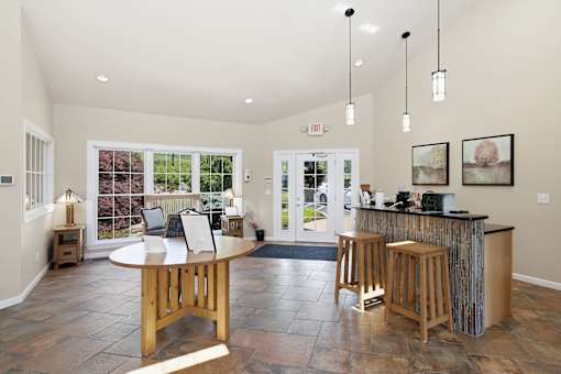 A well-lit room with a bar and a view of a garden outside.