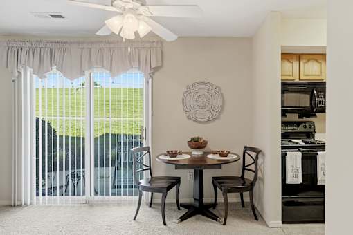 A dining room with a table set for two and a view of a green lawn outside.