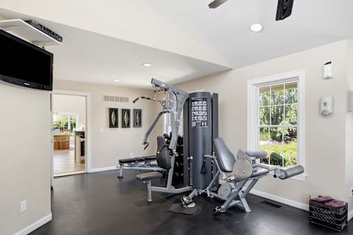 A community gym with a television, weights, and exercise equipment.