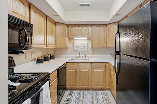 A kitchen with wooden cabinets and a black refrigerator.