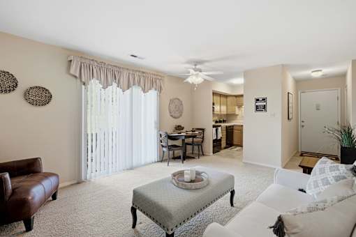 A living room with a brown leather couch, a white sofa, a coffee table, and a dining table with chairs.