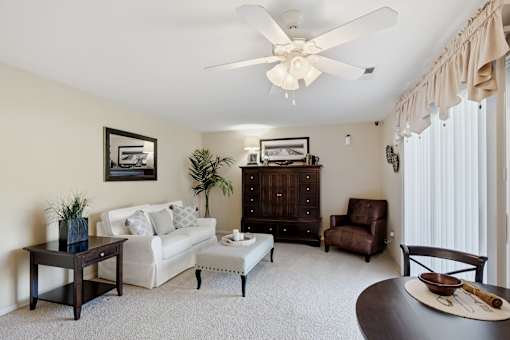 A living room with a white couch, a coffee table, and a ceiling fan.