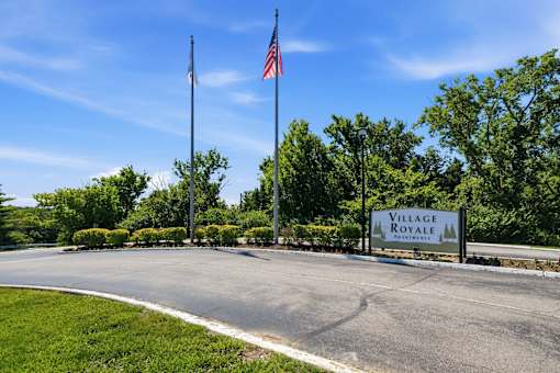 A sign for Village Royale is displayed in front of a grassy area.