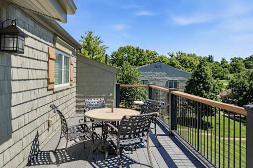 A patio with a table and chairs is on a sunny day.