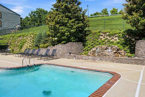 A pool with a waterfall and a stone wall.