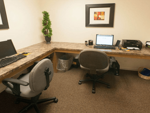 a desk with two chairs and a laptop computer