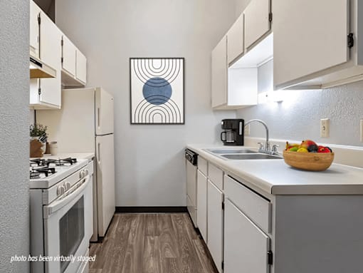 Apartment kitchen with a stove, sink, dishwasher, and cabinets.