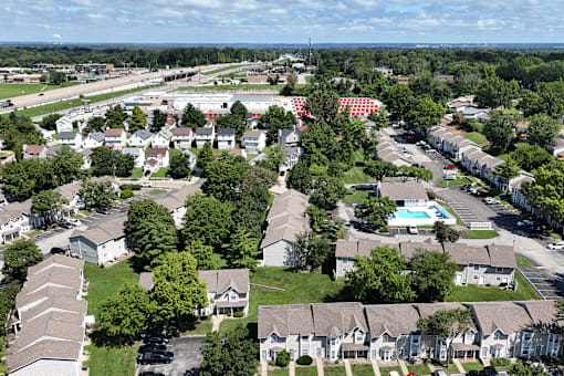 A bird's eye view of a residential area with houses, trees, and a pool.