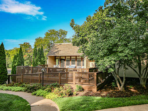 A house with a deck and trees in the front yard.