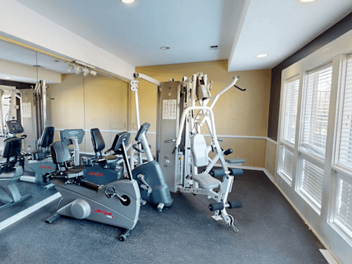 A gym with a treadmill, elliptical trainer and a weight machine.