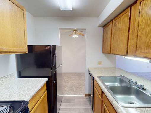 A kitchen with a black refrigerator and wooden cabinets.