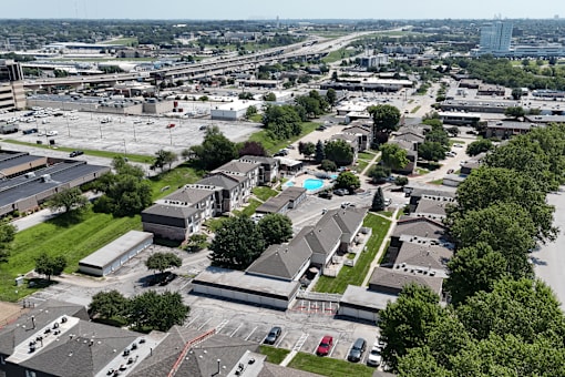 A bird's eye view of a residential area with houses, trees, and cars.