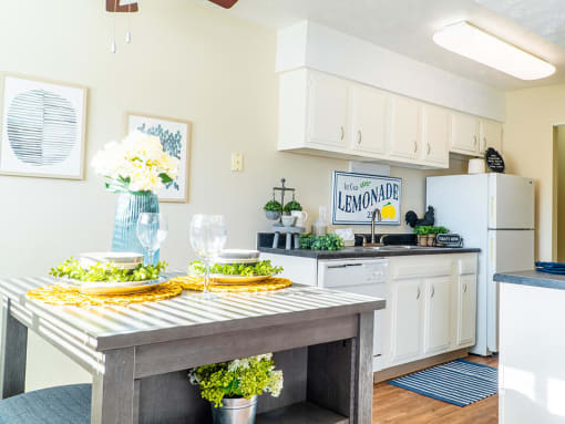 a kitchen with white cabinets and a wooden table with plates and glasses on it