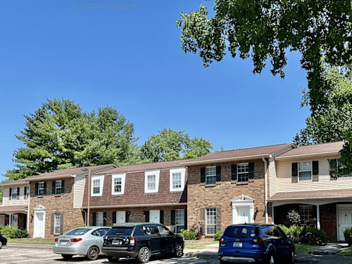 A row of townhouses with cars parked in front.