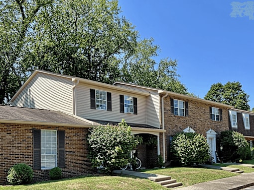 A residential house with a front yard and a tree.