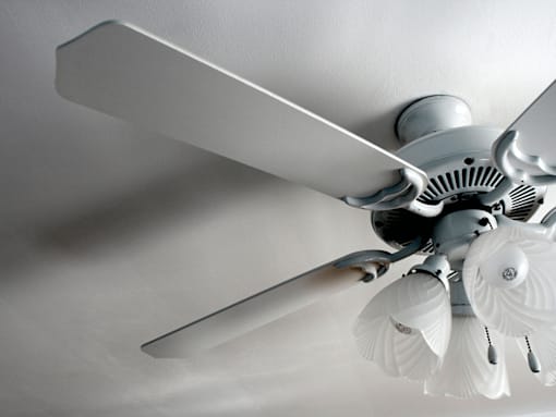 A white ceiling fan with a light fixture is mounted on a white ceiling.
