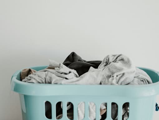 A light blue laundry basket filled with a pile of clothes.