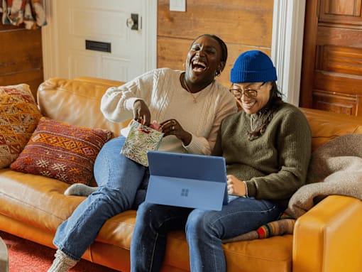 Two people sitting on a couch with a laptop.